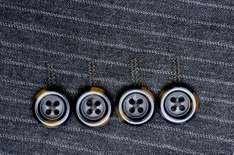 Close up of four buttons on a pin-striped suit jacket