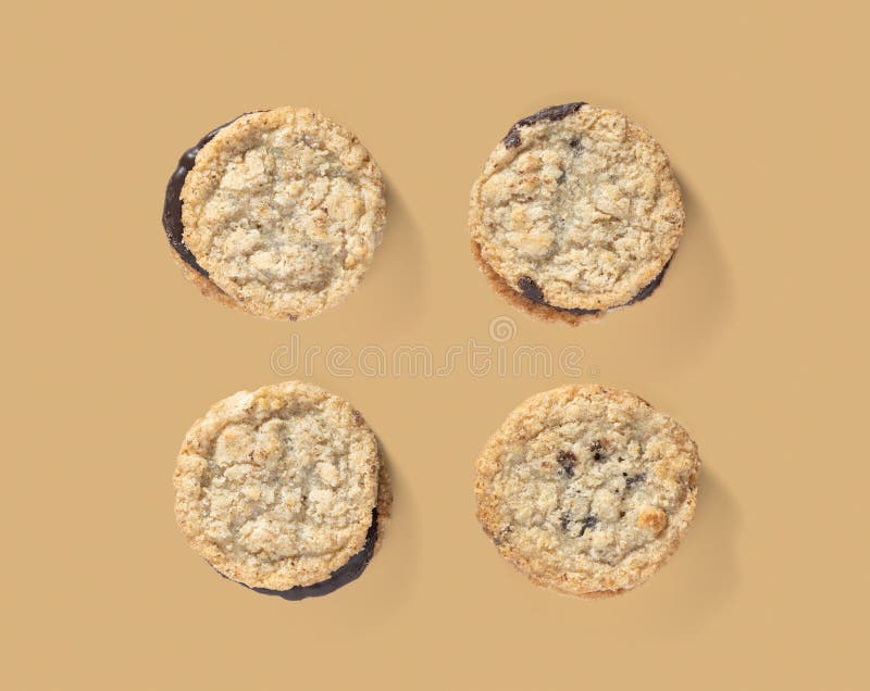 Four chocolate chip cookies arranged in a neat pattern on a brown background. stock photo
