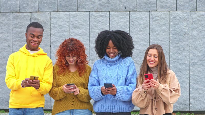 Four friends of different ethnicities chatting with their smartphones