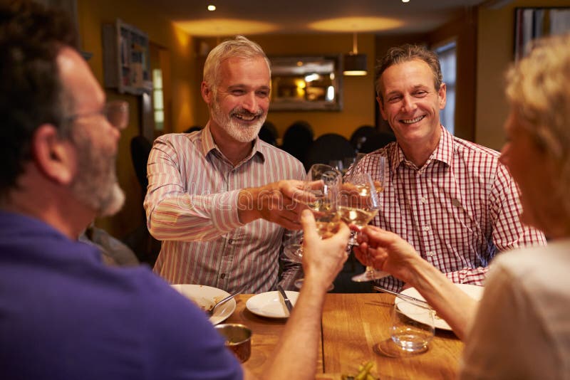 Four friends making a toast during a meal at a restaurant