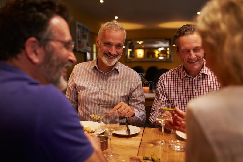 Four friends talking together during a meal at a restaurant