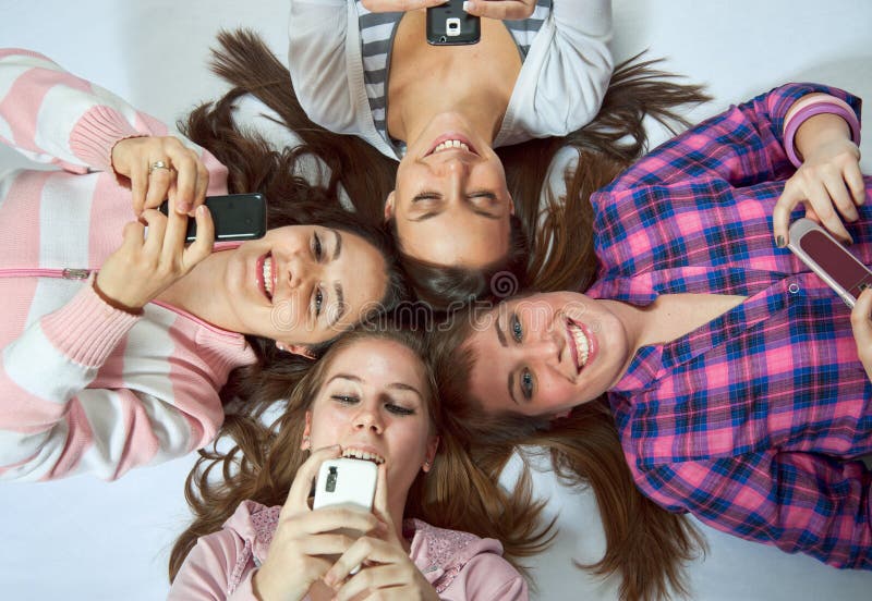 Four girls lying on the floor with cellphones