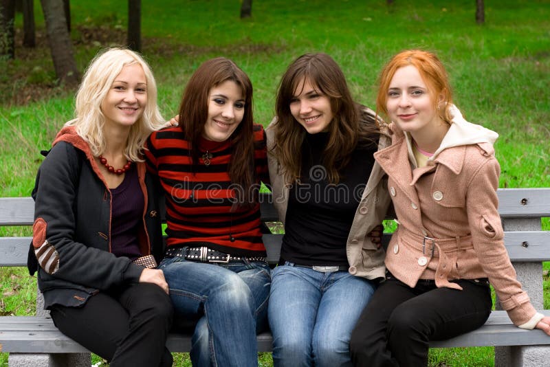 Four girls sitting on a park bench