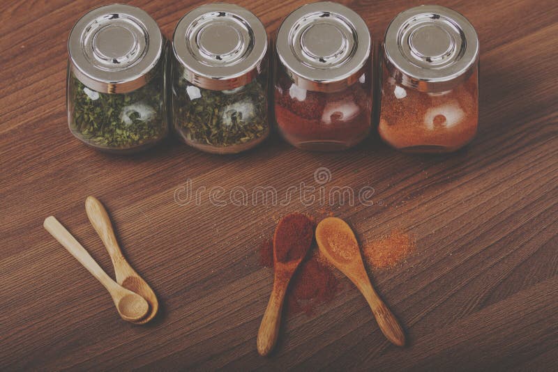 Four Glass Jar with Spices and Four Wooden Spoon on the Table Stock