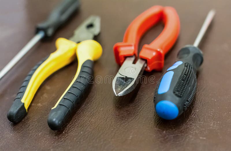 Four hand tools home repair furniture electricians base two screwdrivers pliers and nippers close-up on a dark background