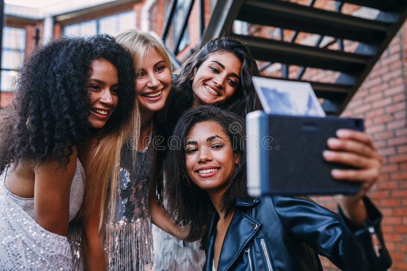 Four happy female friends taking an instant photo stock image Four happy female friends taking an instant photo stock image