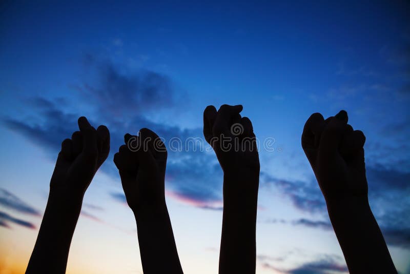 Four clenched fists raised against blue sky. Four clenched fists raised against blue sky