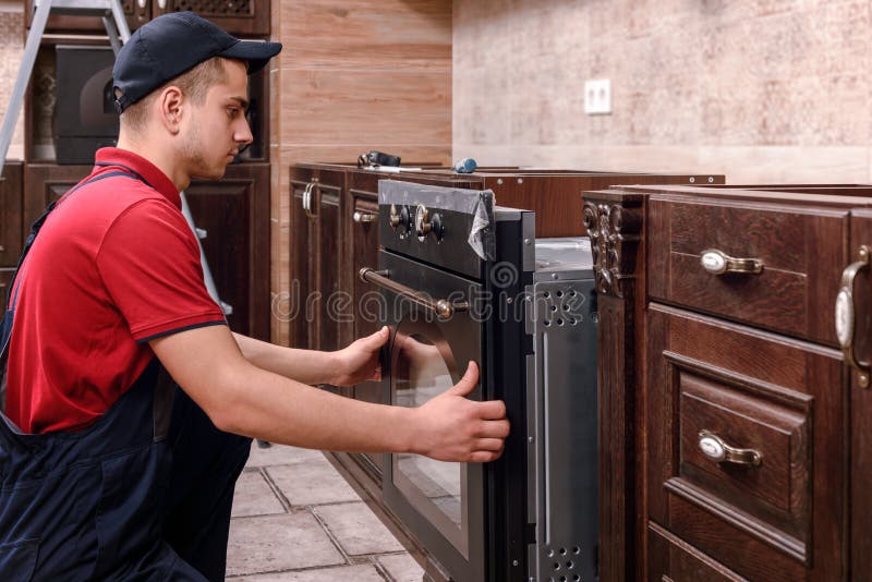 Four se r?unissant de travailleur professionnel Installation des meubles de cuisine photo stock Four se r?unissant de travailleur professionnel Installation des meubles de cuisine photo stock