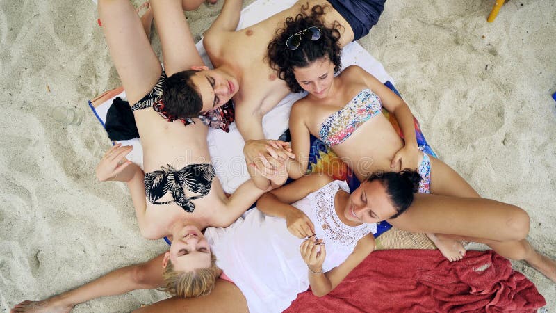 four teenage friends lying on sandy beach and holding by hands stock photography four teenage friends lying on sandy beach and holding by hands stock photography