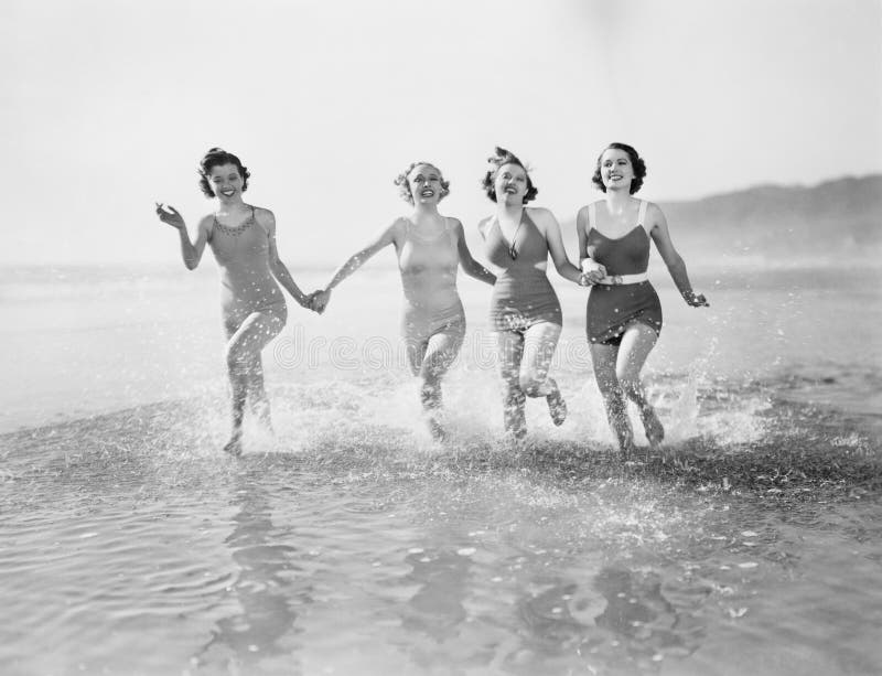 Quattro donne in esecuzione in acqua in spiaggia (a Tutte le persone rappresentate sono più in vita e non residenziale esistente.