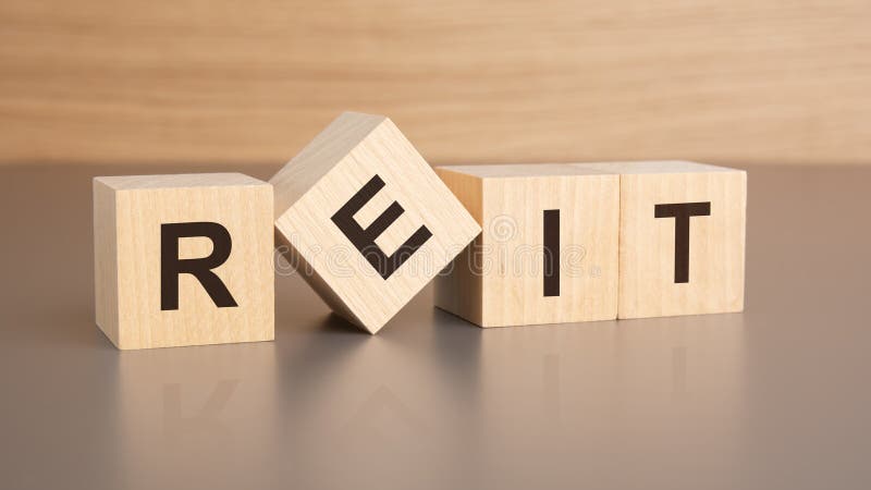 Four wooden cubes with the letters REIT on the bright surface of a brown table, business concept stock photo