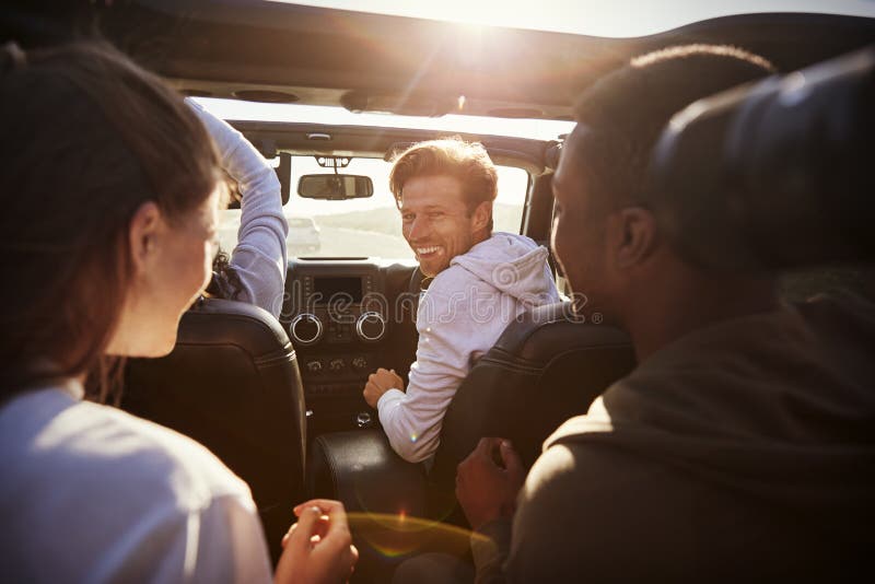 Four young adult friends together in a car on a road trip.