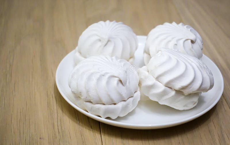 Four zephyr marshmallows on a wooden table royalty free stock image