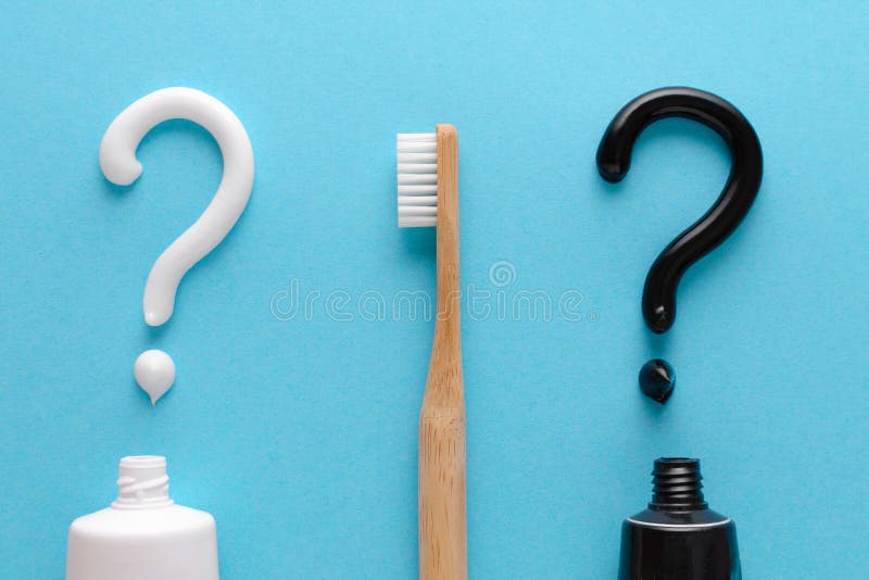 Frage von der wei? en und schwarzen Zahnpasta, Z? hne interessieren sich Konzept, h? lzerne Zahnb? rste auf blauem Hintergrund stockfotos