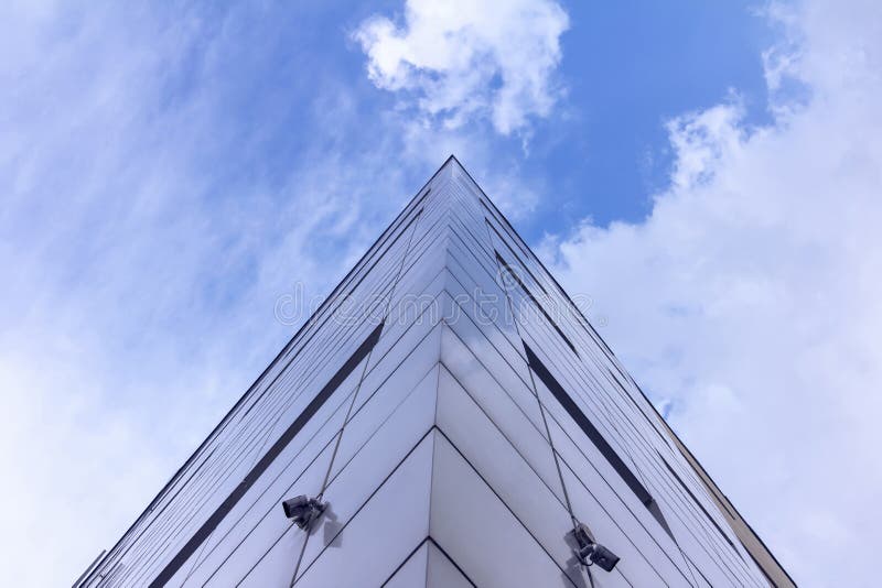 Fragment av fasaden av abstrakt modern kommersiell arkitektur, hörnet av väggarna under en blå molnig himmel arkivfoton Fragment av fasaden av abstrakt modern kommersiell arkitektur, hörnet av väggarna under en blå molnig himmel arkivfoton