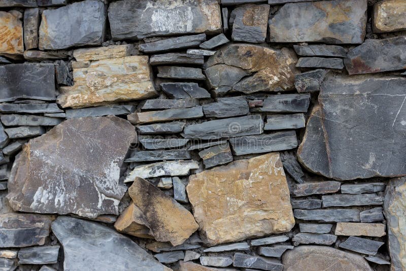 Fragment av väggen som göras av stenar av olik typer och form arkivfoto Fragment av väggen som göras av stenar av olik typer och form arkivfoto