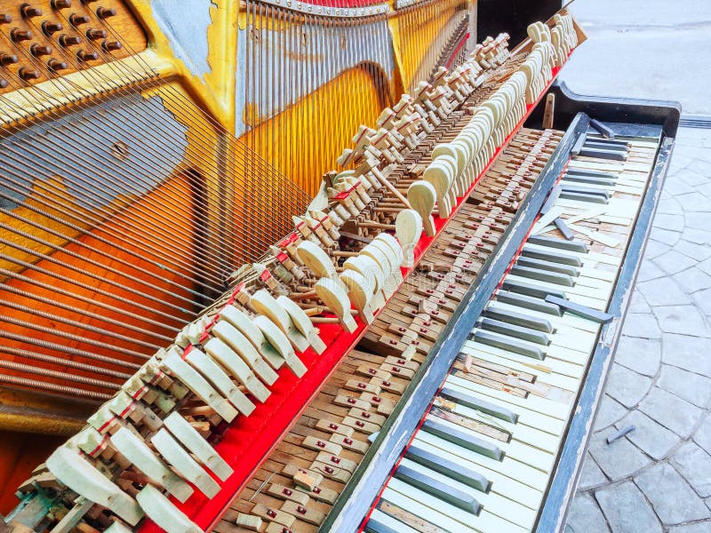 A fragment of an old broken piano with a missing wall and broken keys. Front view stock photo