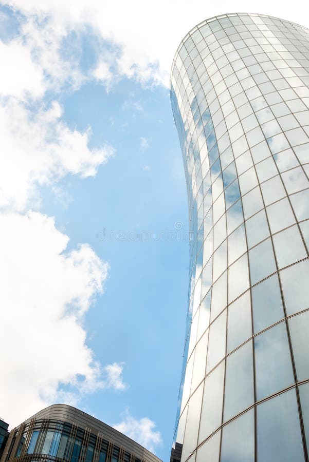 Fragment of a stylish modern high-rise building in St. Petersburg against the blue sky with clouds. The building has a glazed royalty free stock image.