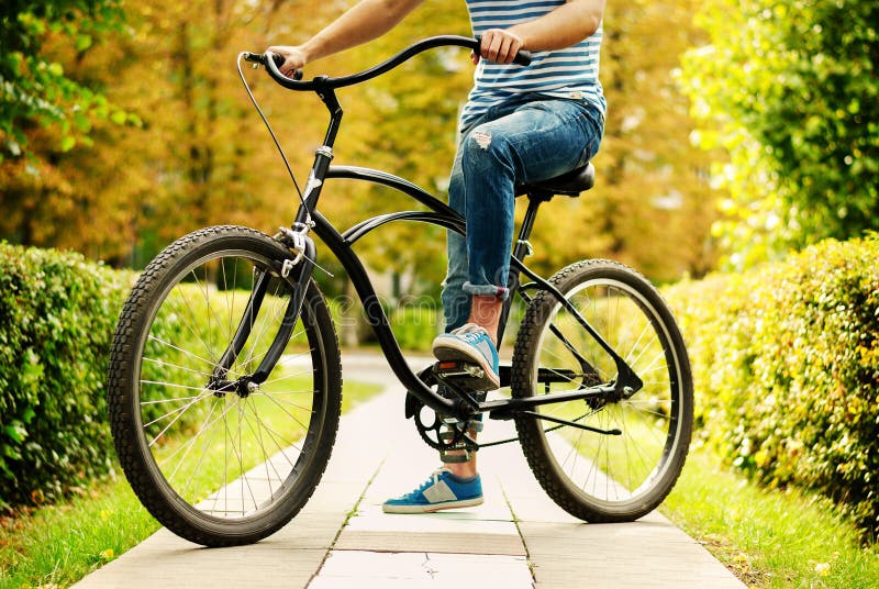 A fragment of a young man sitting on the bike