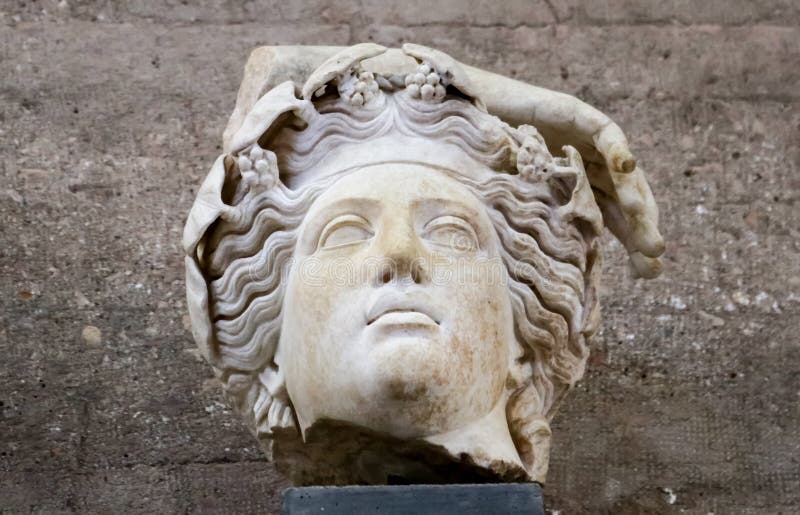 Fragmento de la estatua romana - dios de Corinto antiguo Grecia con las flores o las uvas en pelo ondulado y pieza de una mano imagen de archivo Fragmento de la estatua romana - dios de Corinto antiguo Grecia con las flores o las uvas en pelo ondulado y pieza de una mano imagen de archivo