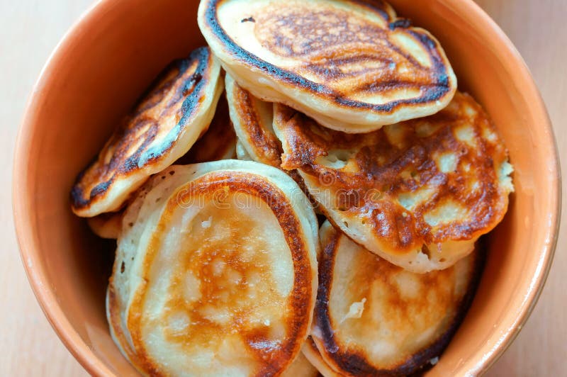 Pancakes in a deep bowl, fragrant pancakes in a plate, round small pancakes in a deep plate stock photography Pancakes in a deep bowl, fragrant pancakes in a plate, round small pancakes in a deep plate stock photography