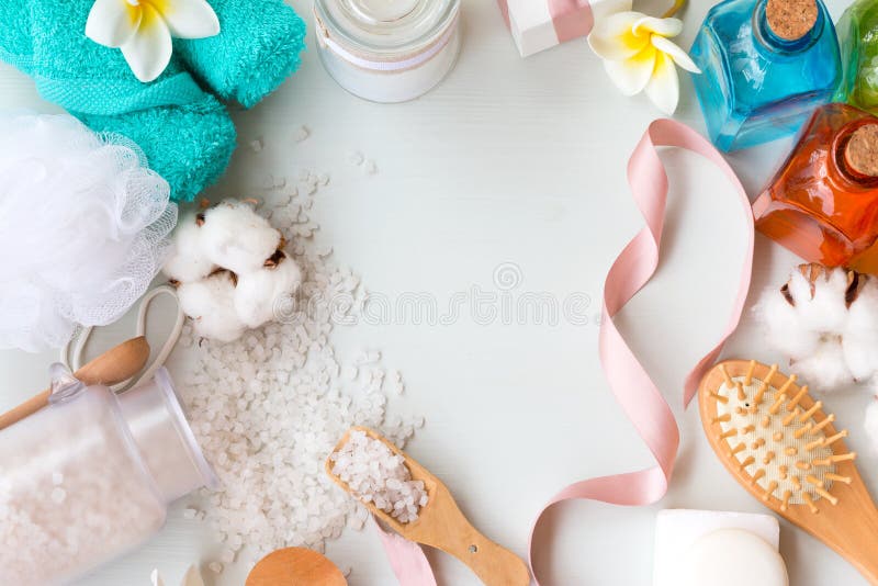 Frame of different personal hygiene objects on white background. Bath salt, comb, blue towels and cotton flower with copy space.