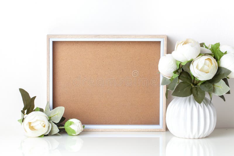 Frame mock up and plants in a vase on on the table. White colors. Greeting card. Background with copy space.