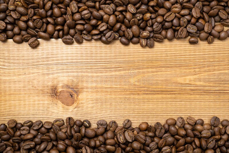 Frame of scattered coffee beans on wood background with copy space