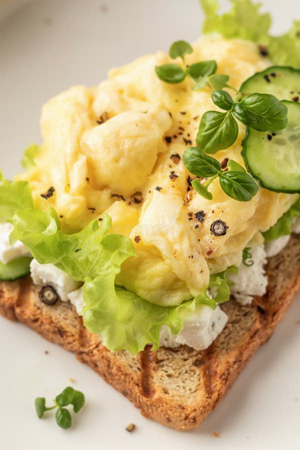 Framlade ägg på grillade rost med salladsblad ost och mikrogreens på plattan nära varandra. Äkta friska frukost fotografering för bildbyråer