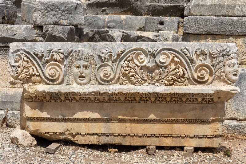 Frammento della facciata con l'immagine di maschere di pietra dell'anfiteatro verde dell'antica città di myra in domanda fotografia stock