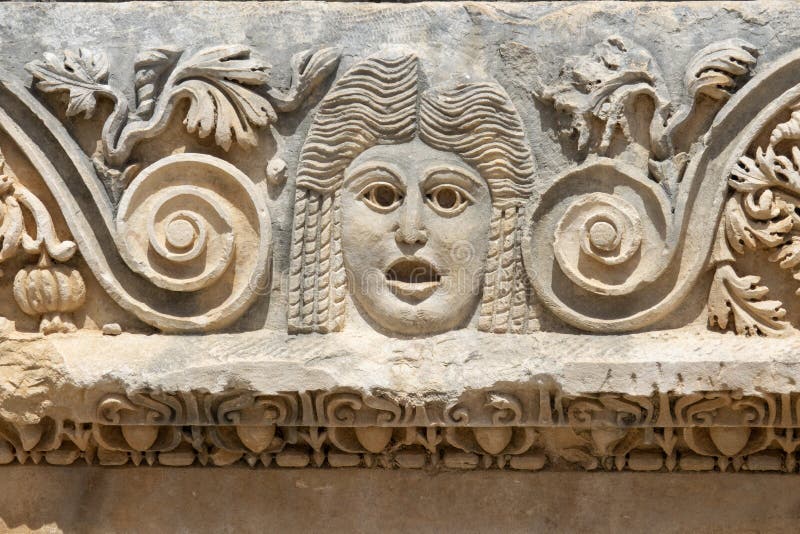 Frammento della facciata con l'immagine di maschere di pietra dell'anfiteatro verde dell'antica città di myra in domanda fotografie stock