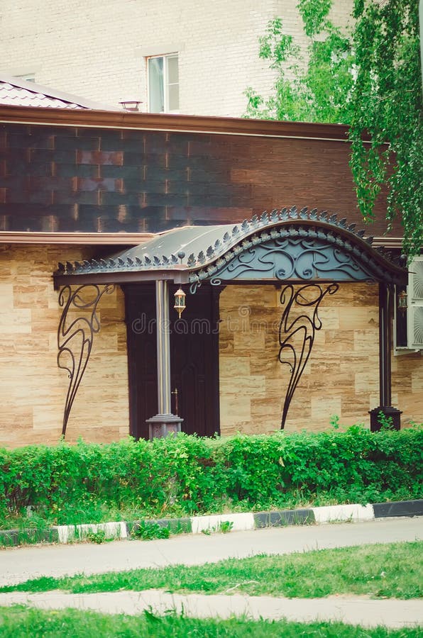 Frammento di bella casa ad un piano, un portico con un baldacchino del ferro fotografia stock Frammento di bella casa ad un piano, un portico con un baldacchino del ferro fotografia stock