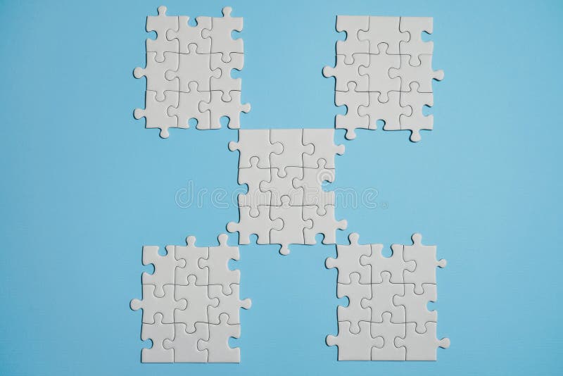 Frammento di un puzzle bianco piegato e un mucchio degli elementi spettinati di puzzle contro lo sfondo di una superficie blu fotografia stock Frammento di un puzzle bianco piegato e un mucchio degli elementi spettinati di puzzle contro lo sfondo di una superficie blu fotografia stock