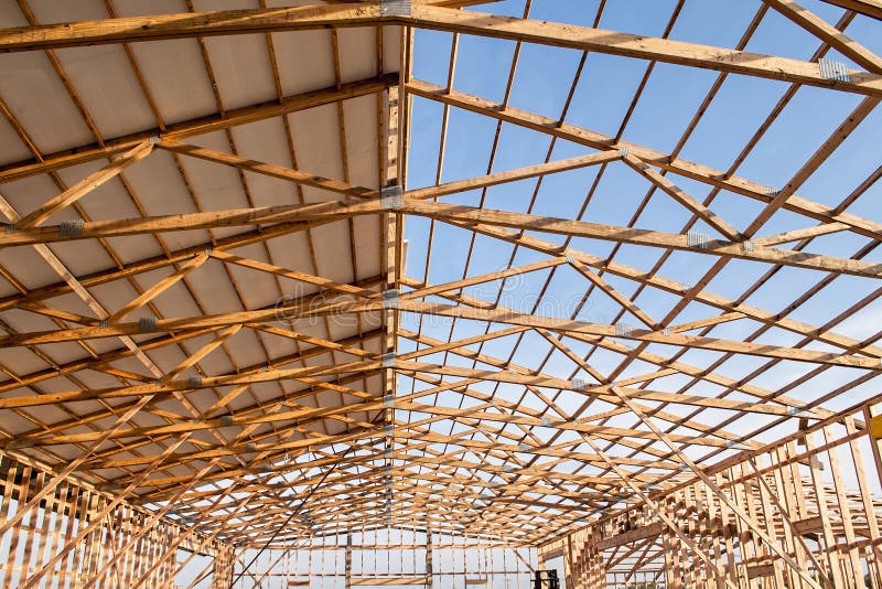 The framming of a new barn under construction with a section of metal roof installed. The framming of a new barn under construction with a section of metal roof installed