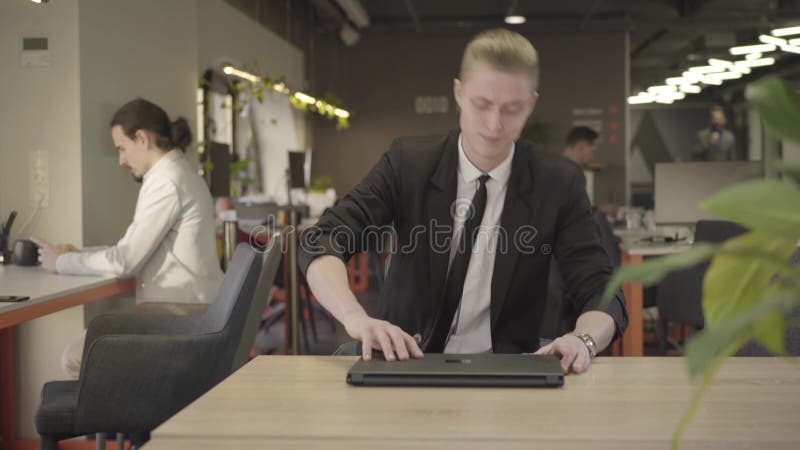 Framsida av koncentrerad rödhårig kaukasisk man som sitter på stol vid bordet och öppnar en bärbar dator Förtroende man i