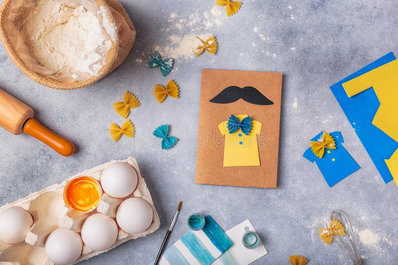 Framställning av hälsningkortet för faderdag Skjorta med fjärilen från pasta Kort från papper moustache Barns konstprojekt royaltyfri bild Framställning av hälsningkortet för faderdag Skjorta med fjärilen från pasta Kort från papper moustache Barns konstprojekt royaltyfri bild