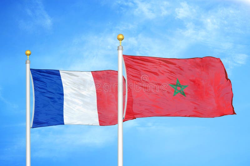 France and Morocco Two Flags on Flagpoles and Blue Cloudy Sky Stock