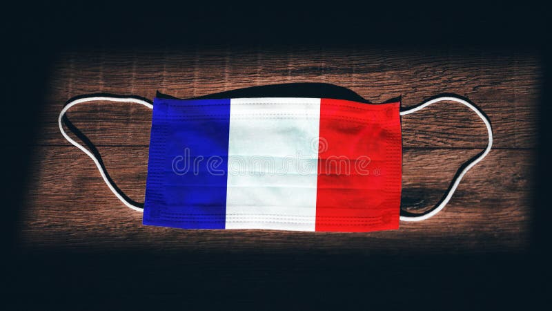 France National Flag at medical, surgical, protection mask on black wooden background. Coronavirus Covidâ€“19, Prevent infection