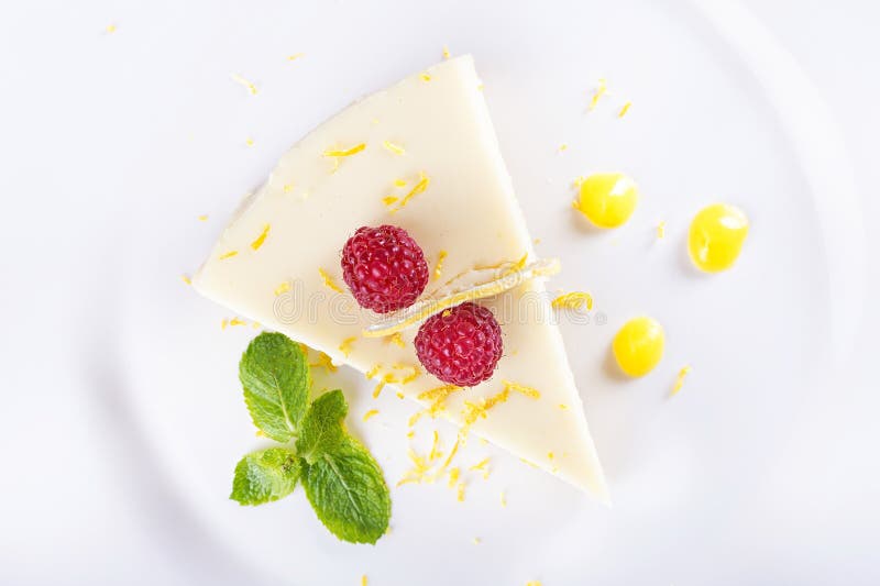 Piece French lemon tart, garnished with fresh raspberries, mint and slice of lemon, top view. Piece French lemon tart, garnished with fresh raspberries, mint and slice of lemon, top view