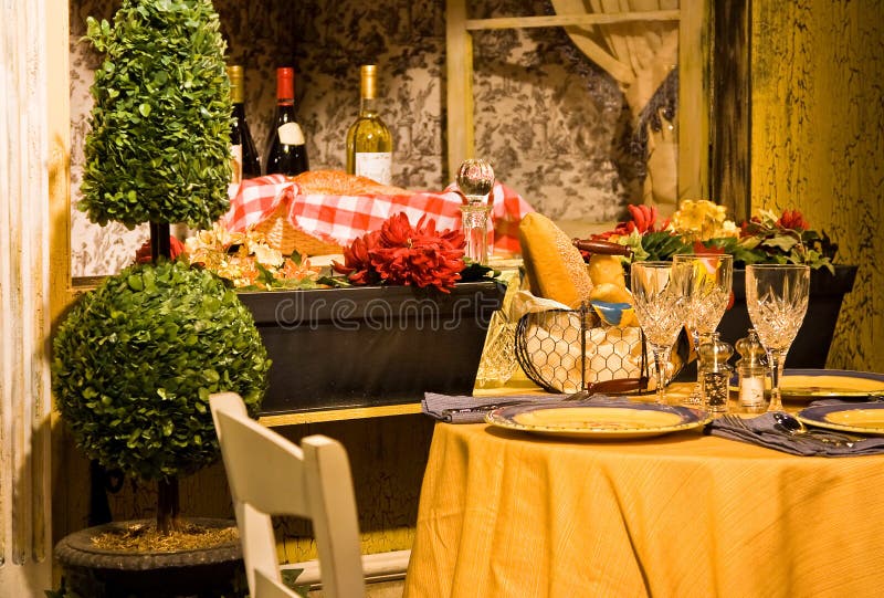 A cozy and rustic French style lunch/dinner table in front of a window with bottles of wine. Typical bistro. A cozy and rustic French style lunch/dinner table in front of a window with bottles of wine. Typical bistro.