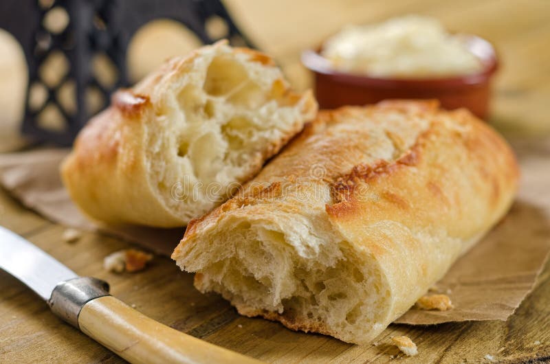 A freshly baked loaf of crispy french bread with butter and knife. A freshly baked loaf of crispy french bread with butter and knife.