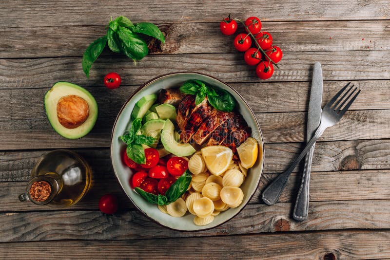 Frango grelhado com massa orecchiette, tomate fresco e folhas de manjericão foto de stock