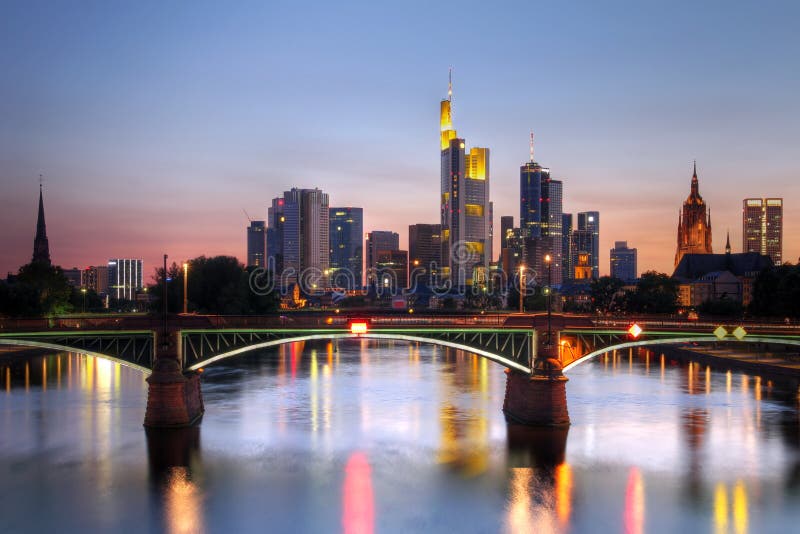 River view at twilight of Frankfurt am Main in Germany (Hesse). Most iconic buildings (skyscrapers) are visible, together with the tower of Saint Bartholomews Cathedral, while the Obermainbrucke (Bridge) is providing the foreground. River view at twilight of Frankfurt am Main in Germany (Hesse). Most iconic buildings (skyscrapers) are visible, together with the tower of Saint Bartholomews Cathedral, while the Obermainbrucke (Bridge) is providing the foreground.