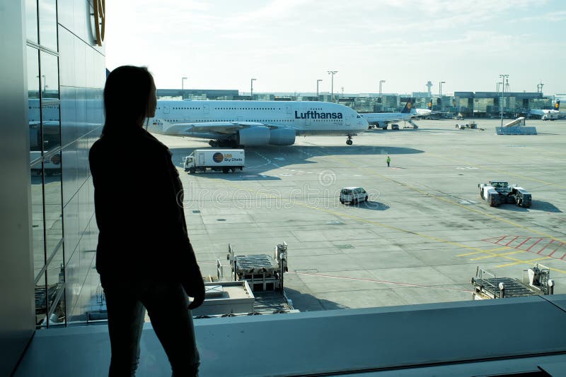 Frankfurt am Main, Germany - October 11, 2015: girl silhouette look at planes on airdrome ground on sunny day. Woman in airport. T