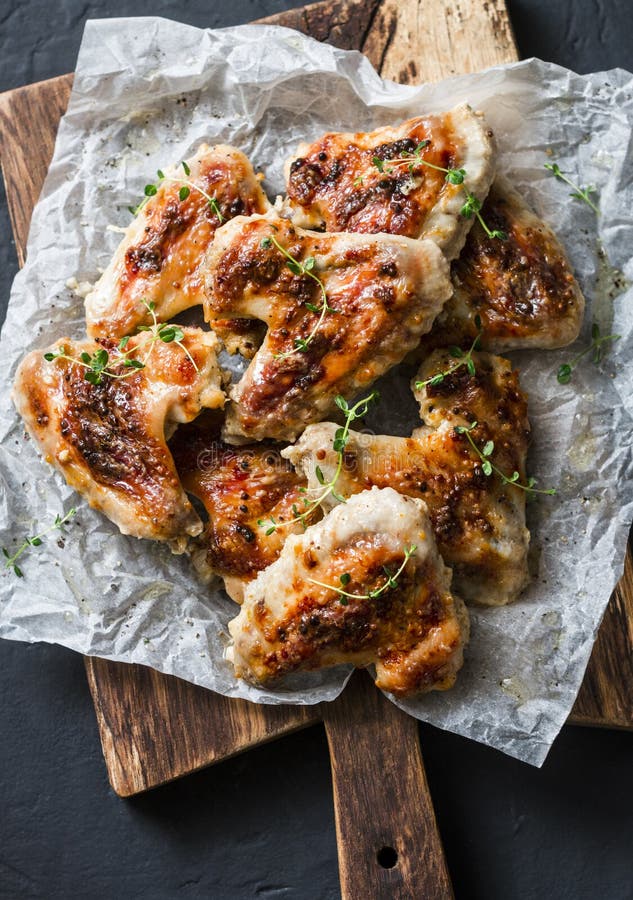 Französische Senfmarinade briet Hühnerflügel auf hölzernem hackendem Brett - köstliche Aperitifs, Tapas auf dunklem Hintergrund stockbild Französische Senfmarinade briet Hühnerflügel auf hölzernem hackendem Brett - köstliche Aperitifs, Tapas auf dunklem Hintergrund stockbild