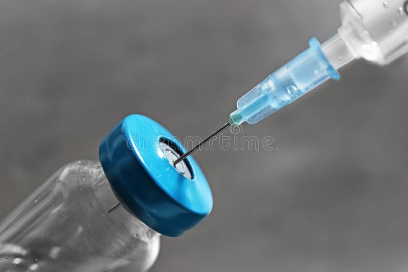 Frasco con la vacuna y la jeringuilla en fondo gris