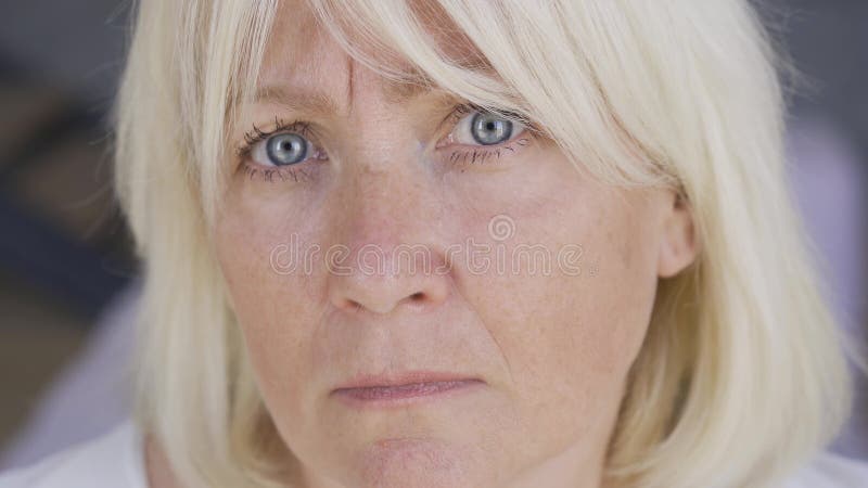 Frase de una mujer madura asustada y frustrada que mira la cámara. La mujer con los ojos azules y el pelo rubio en casa metrajes