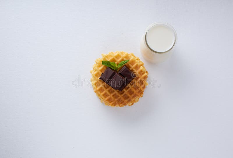 Frasiga belgiska dillandear med chokladchiper på en vit texturerad yttersida Den lilla exponeringsglastillbringaren med mjölkar arkivbilder Frasiga belgiska dillandear med chokladchiper på en vit texturerad yttersida Den lilla exponeringsglastillbringaren med mjölkar arkivbilder
