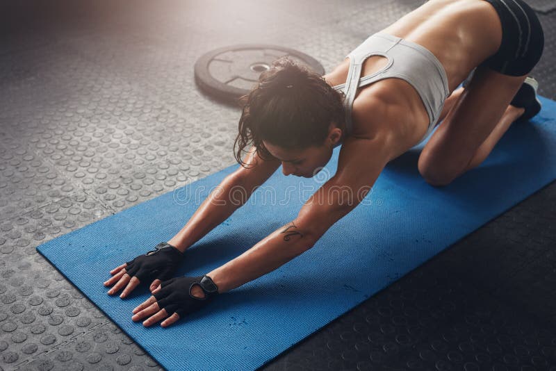 Young woman doing stretching exercises in a health club. Woman on fitness mat doing stretching workout at gym. Young woman doing stretching exercises in a health club. Woman on fitness mat doing stretching workout at gym.