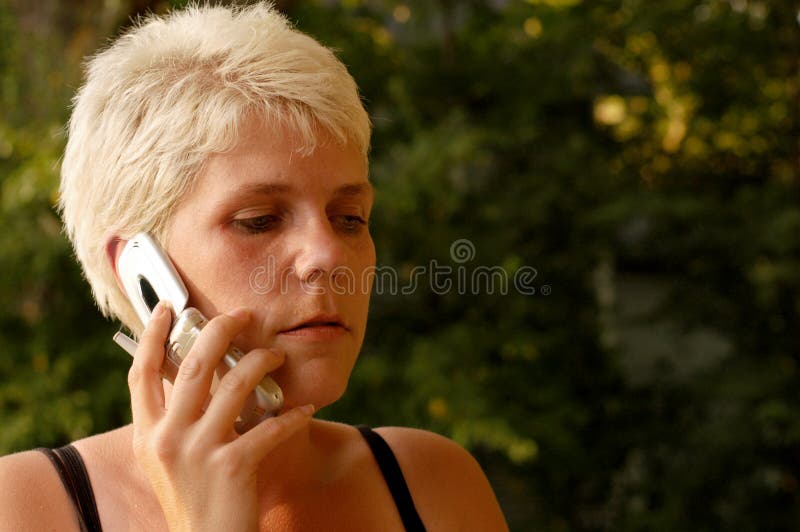 Young woman with short blond hair talking on a cell phone. Young woman with short blond hair talking on a cell phone.